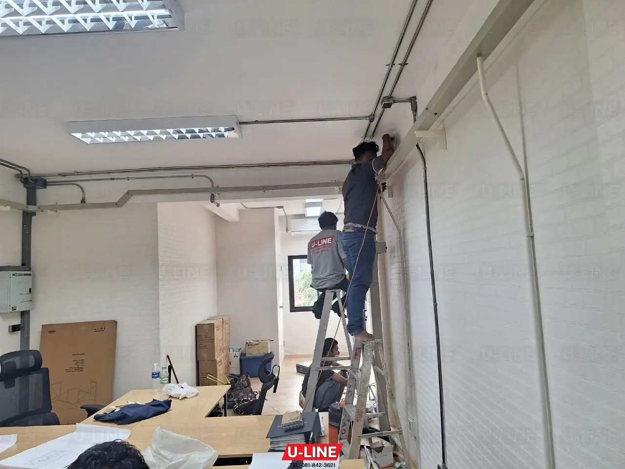 ช่างกำลังเดินท่อและปลั๊กในสำนักงาน